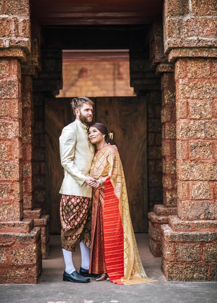 la sposa asiatica e lo sposo caucasico hanno un momento romantico con il vestito thailandese foto