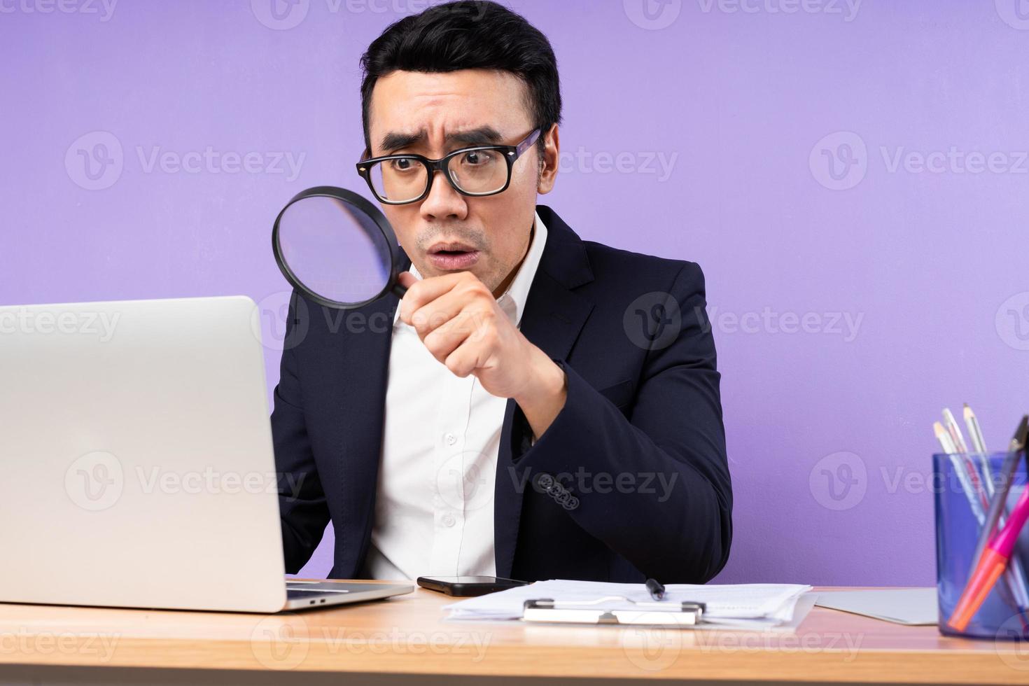 uomo d'affari asiatico ritratto maschile seduto sulla scrivania, isolato su sfondo viola foto