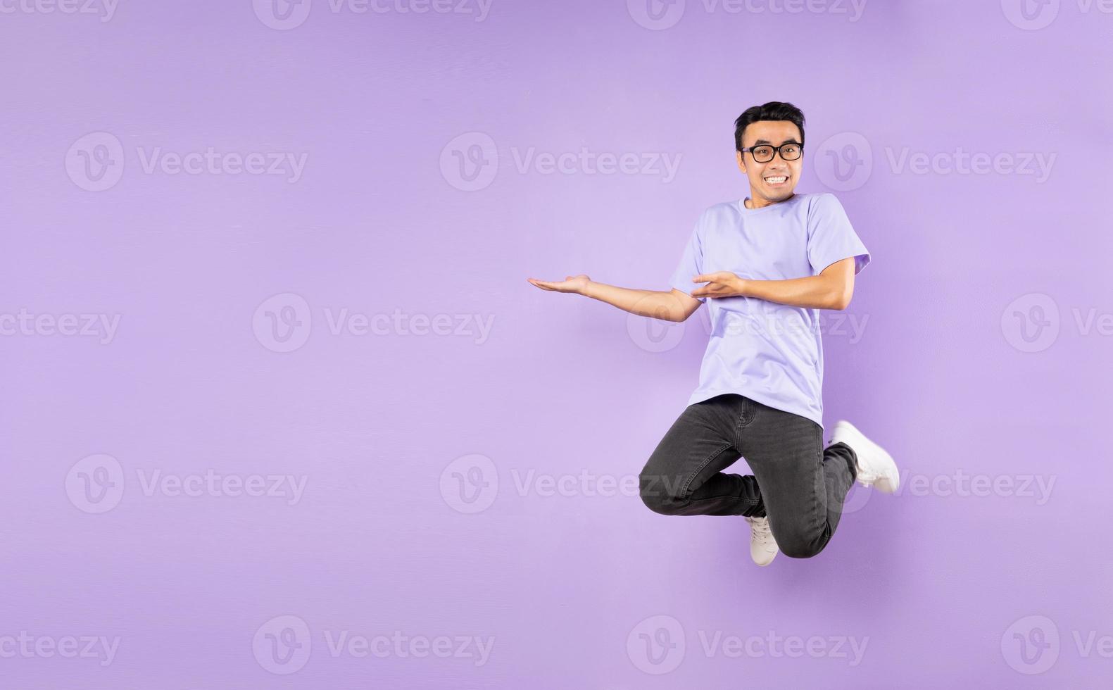 ritratto di un uomo asiatico che salta, isolato su sfondo viola foto