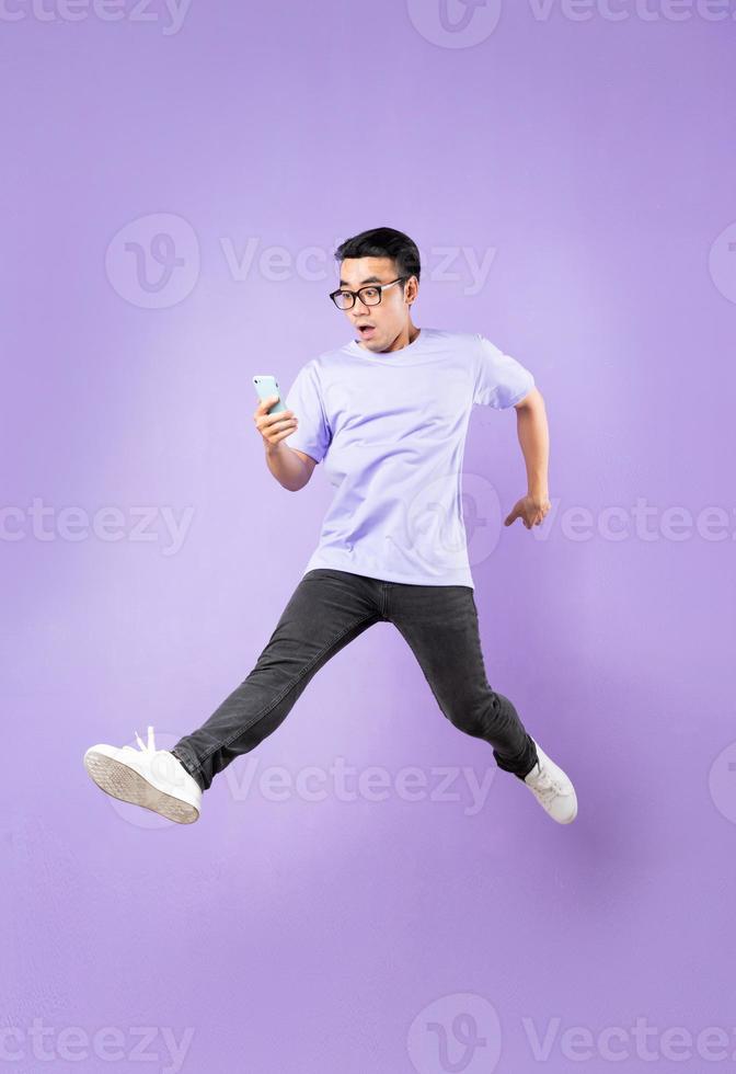 ritratto di un uomo asiatico che salta, isolato su sfondo viola foto
