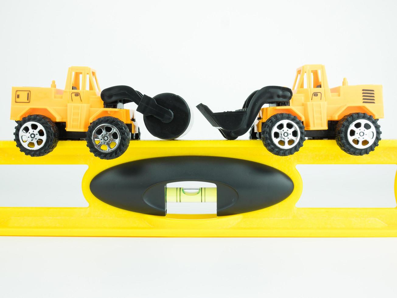 Auto da strada a pressione giocattolo e bulldozer con livello di costruzione su sfondo bianco, concetto di costruzione ingegneristica foto