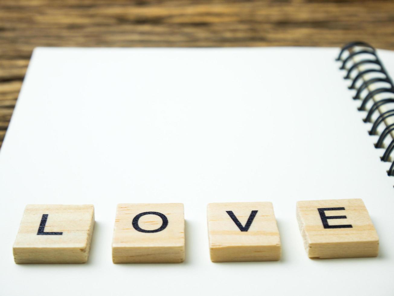 parola d'amore in cubo di legno e taccuino e penna su fondo in legno, san valentino foto