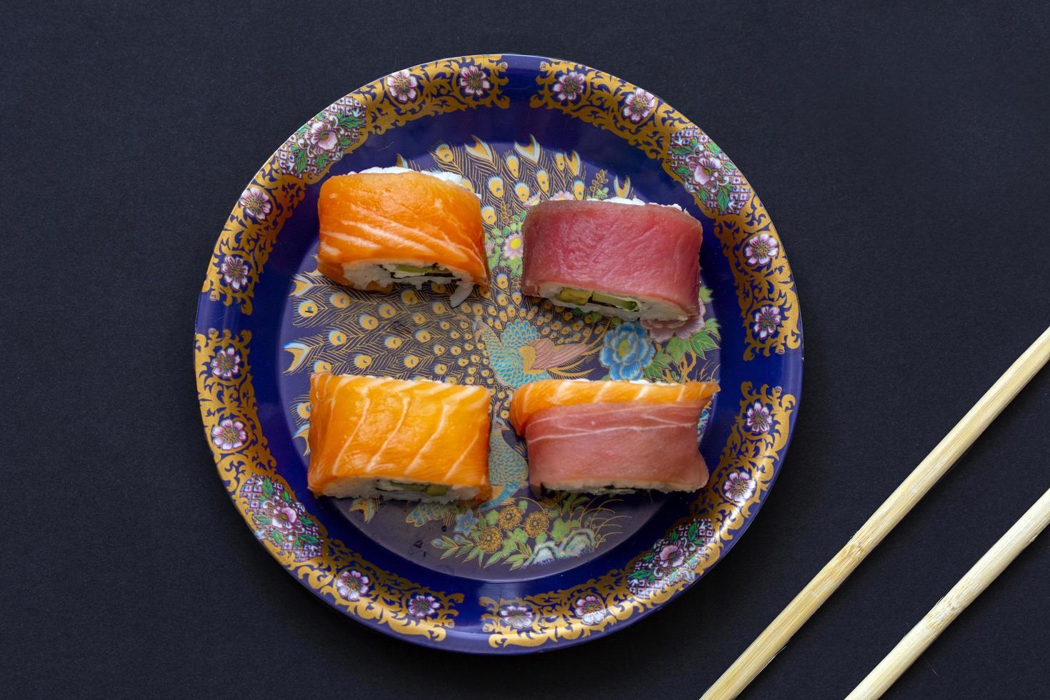 involtini di sushi california con avocado, cetriolo e formaggio avvolti in salmone e tonno foto