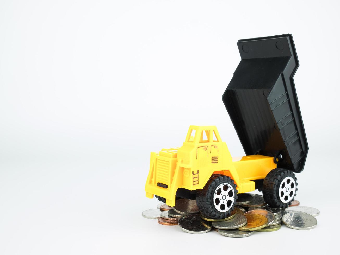 Camion giocattolo con monete su sfondo bianco, business concept foto