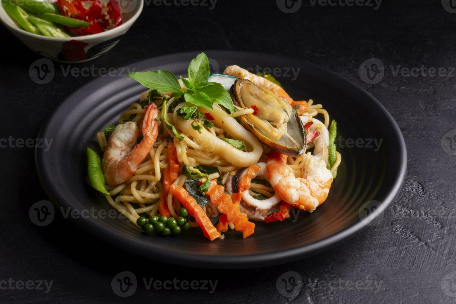 frutti di mare ubriaco spaghetti con gamberetto calamaro vongole chili, e basilico. tailandese cibo. salutare asiatico nel un' piatto su un' nero sfondo tavolo. superiore Visualizza. foto