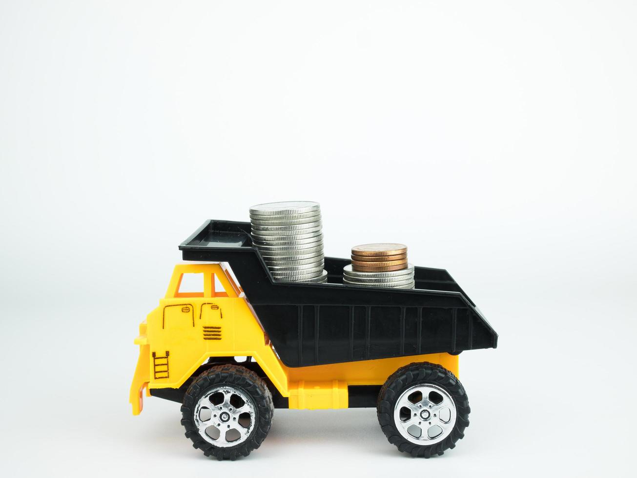 Camion giocattolo con monete su sfondo bianco, business concept foto