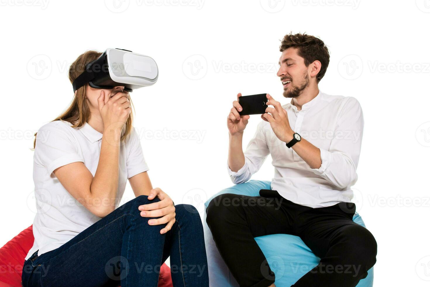 eccitato giovane coppia sperimentare virtuale la realtà seduto su sacchi di fagioli isolato su bianca sfondo foto