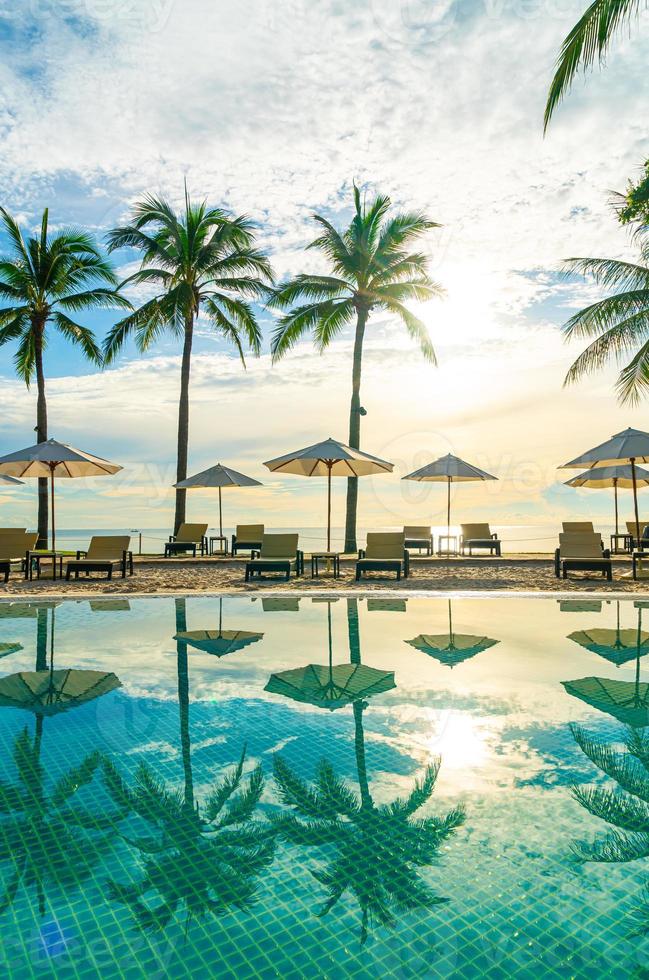 bellissimo ombrellone di lusso e sedia intorno alla piscina all'aperto in hotel e resort con palme da cocco al tramonto o all'alba sky foto