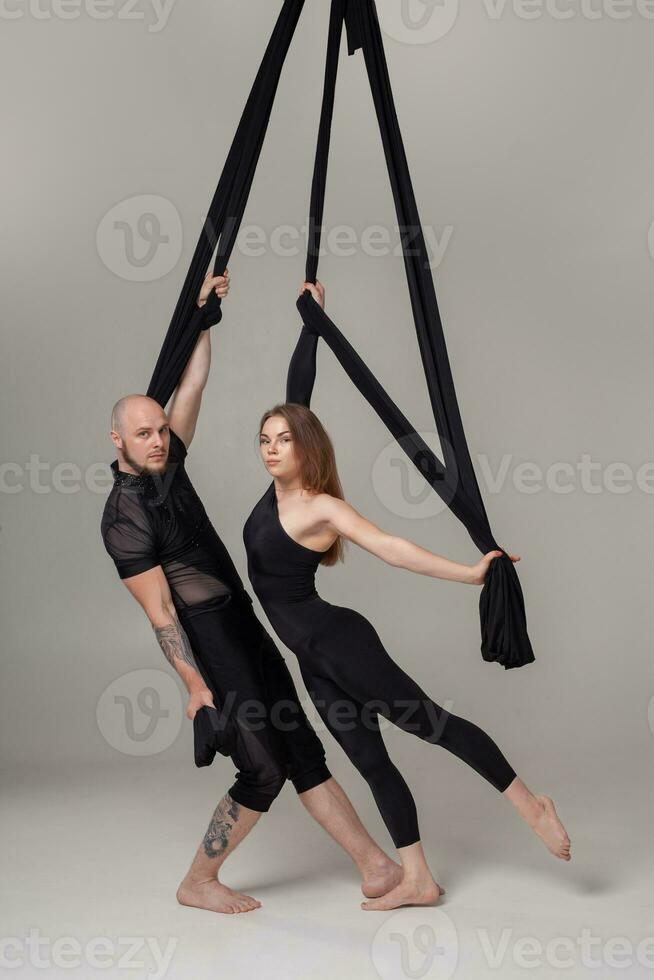 bellissimo ragazza e un atletico uomo nel un' nero sport tute siamo l'esecuzione un acrobatico elementi nel un' studio. foto