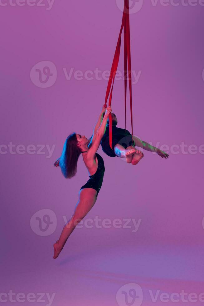 bellissimo ragazza e un atletico uomo nel un' nero sport tute siamo l'esecuzione un acrobatico elementi nel un' studio. foto