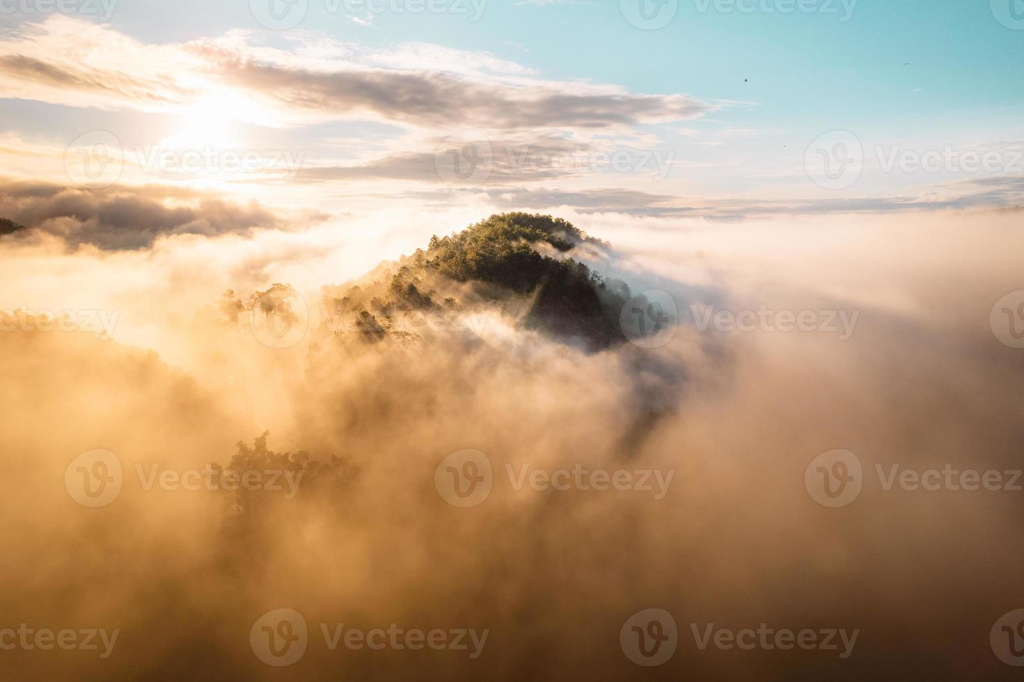 il sole sorge nella nebbia e nelle montagne al mattino foto