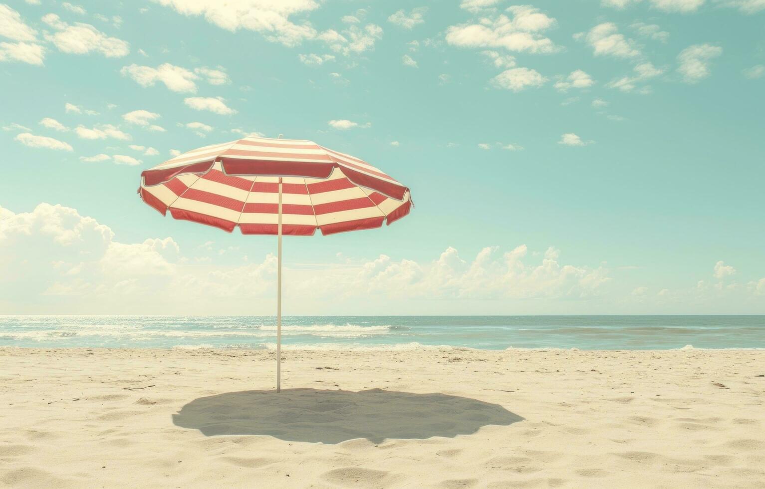 ai generato un' spiaggia scena con un' rosso e bianca a strisce ombrello foto