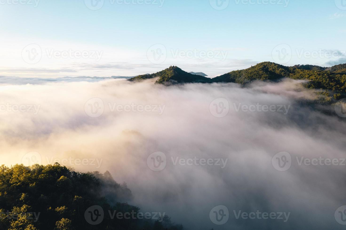 il sole sorge nella nebbia e nelle montagne al mattino foto