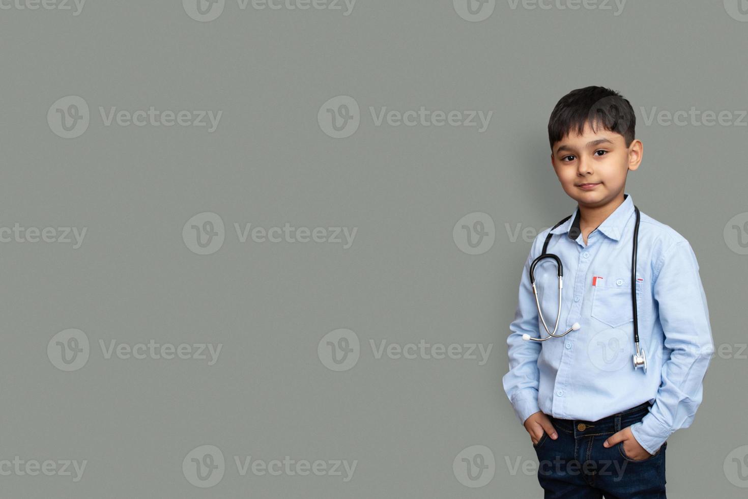 carino piccolo bambino asiatico pakistano ragazzo indossare camicia bianca con stetoscopio che gioca dottore, felice divertente piccolo bambino in età prescolare di razza mista che finge pediatri foto