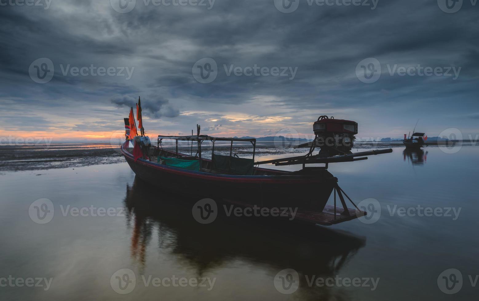 barca da pesca in legno con luci soffuse del cielo al tramonto. foto