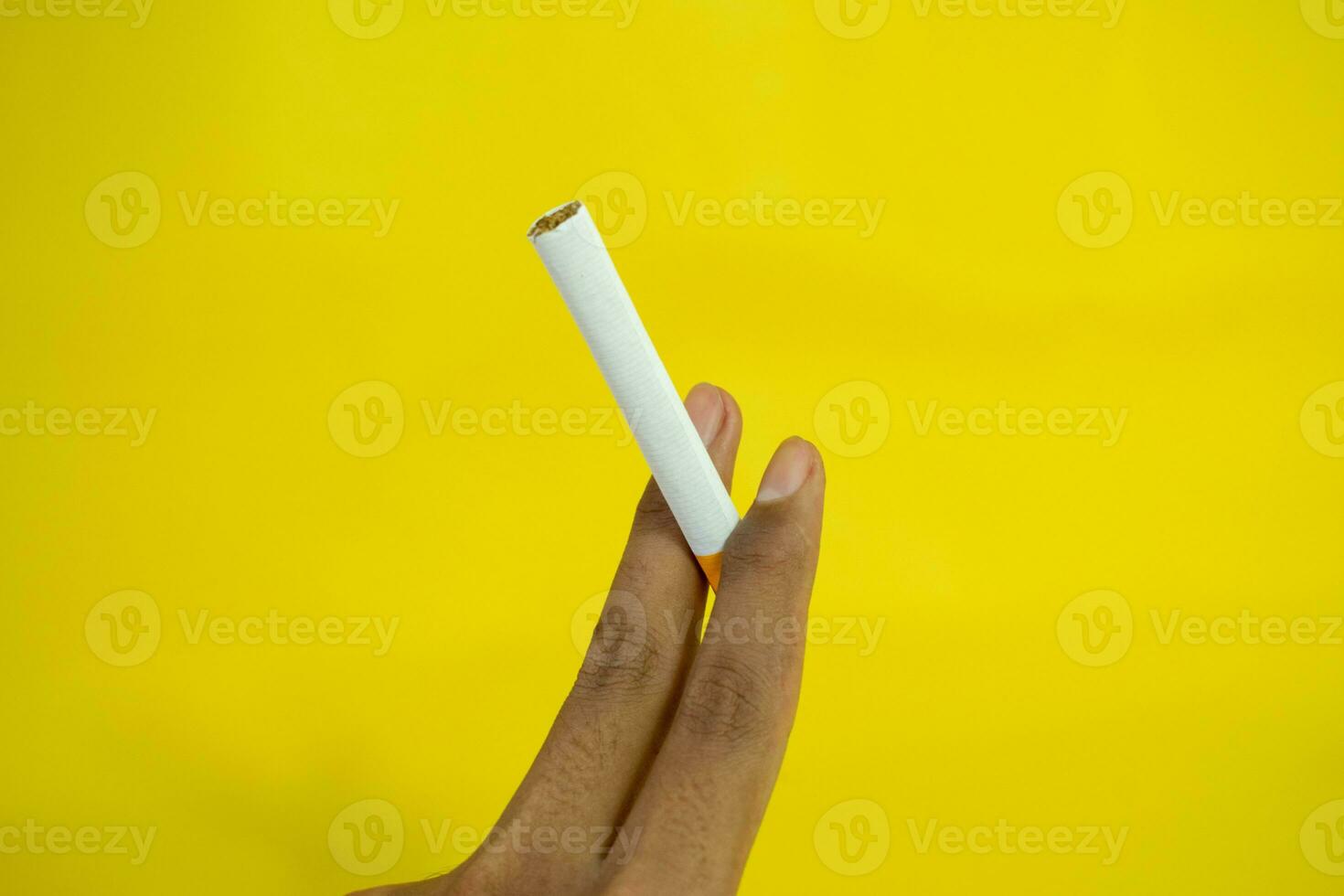 un' uomo mano detiene un' fatto a mano sigaretta su giallo sfondo foto
