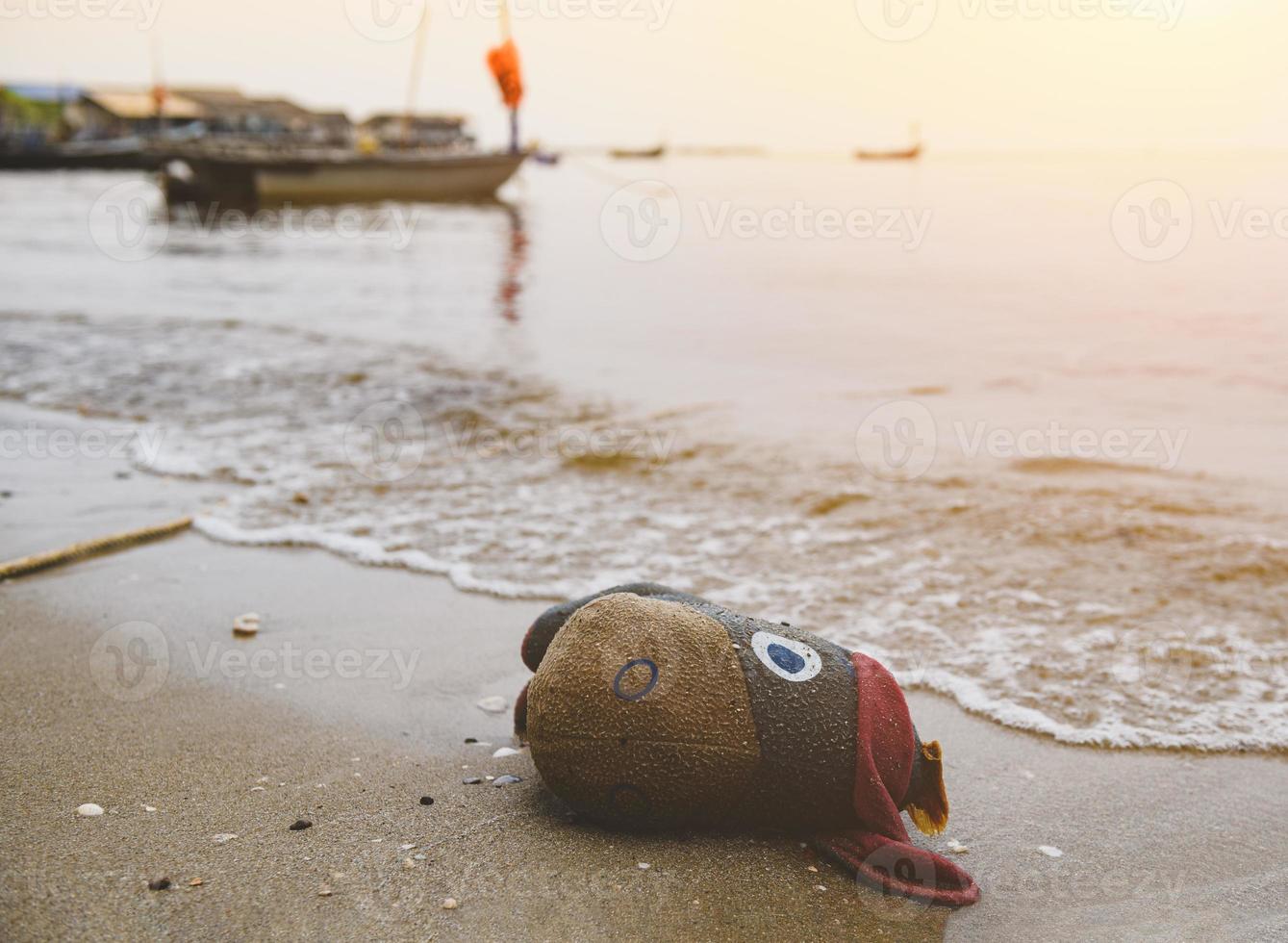 scartare la vecchia bambola di stoffa della spazzatura sulla spiaggia. foto