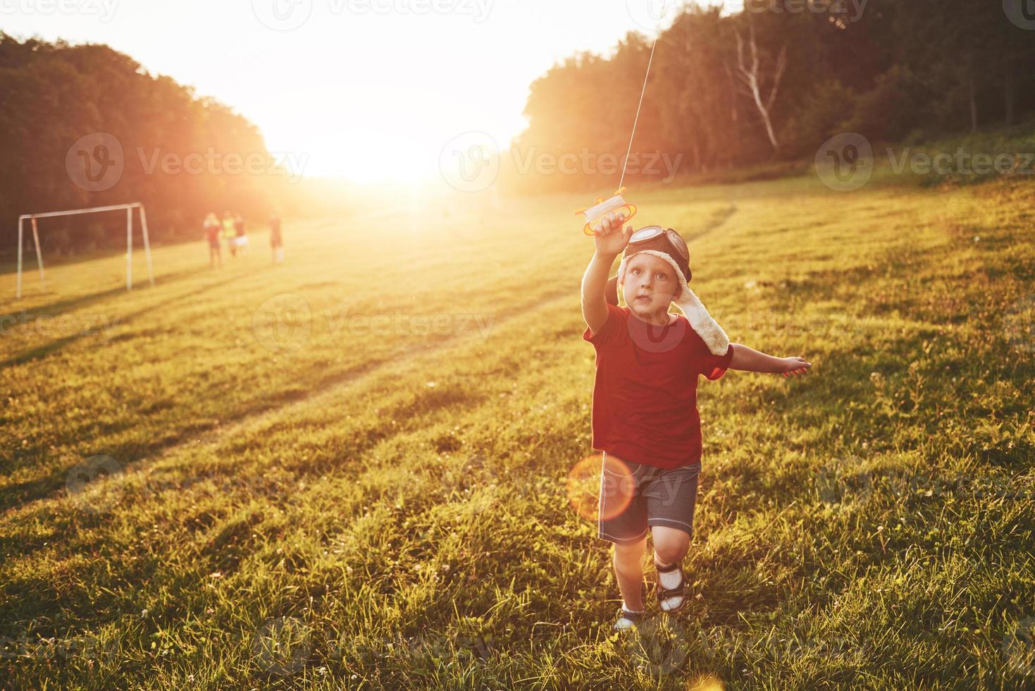 bambino felice lancia un aquilone nel campo al tramonto. ragazzino e ragazza in vacanza estiva foto