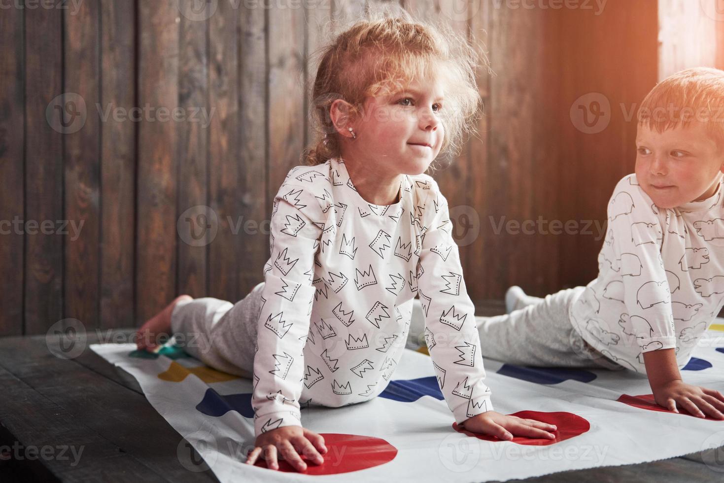 due di bambini felici che giocano a twister in casa. fratello e sorella si divertono in vacanza foto