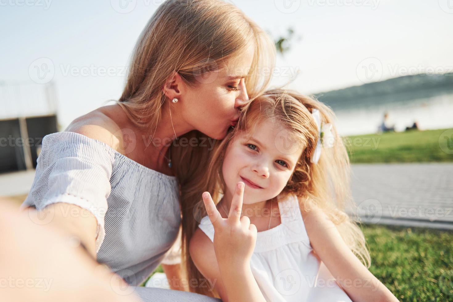 felice giovane madre con una figlia giocosa in un parco vicino all'acqua foto