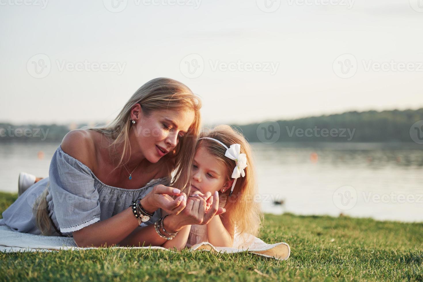 attraente giovane madre felice sdraiata con sua figlia carina sull'erba nel parco. foto