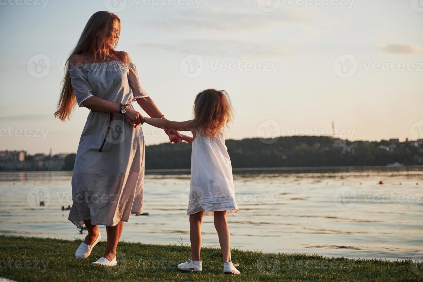 mamma e la sua piccola figlia giocano sull'erba vicino al lago. foto