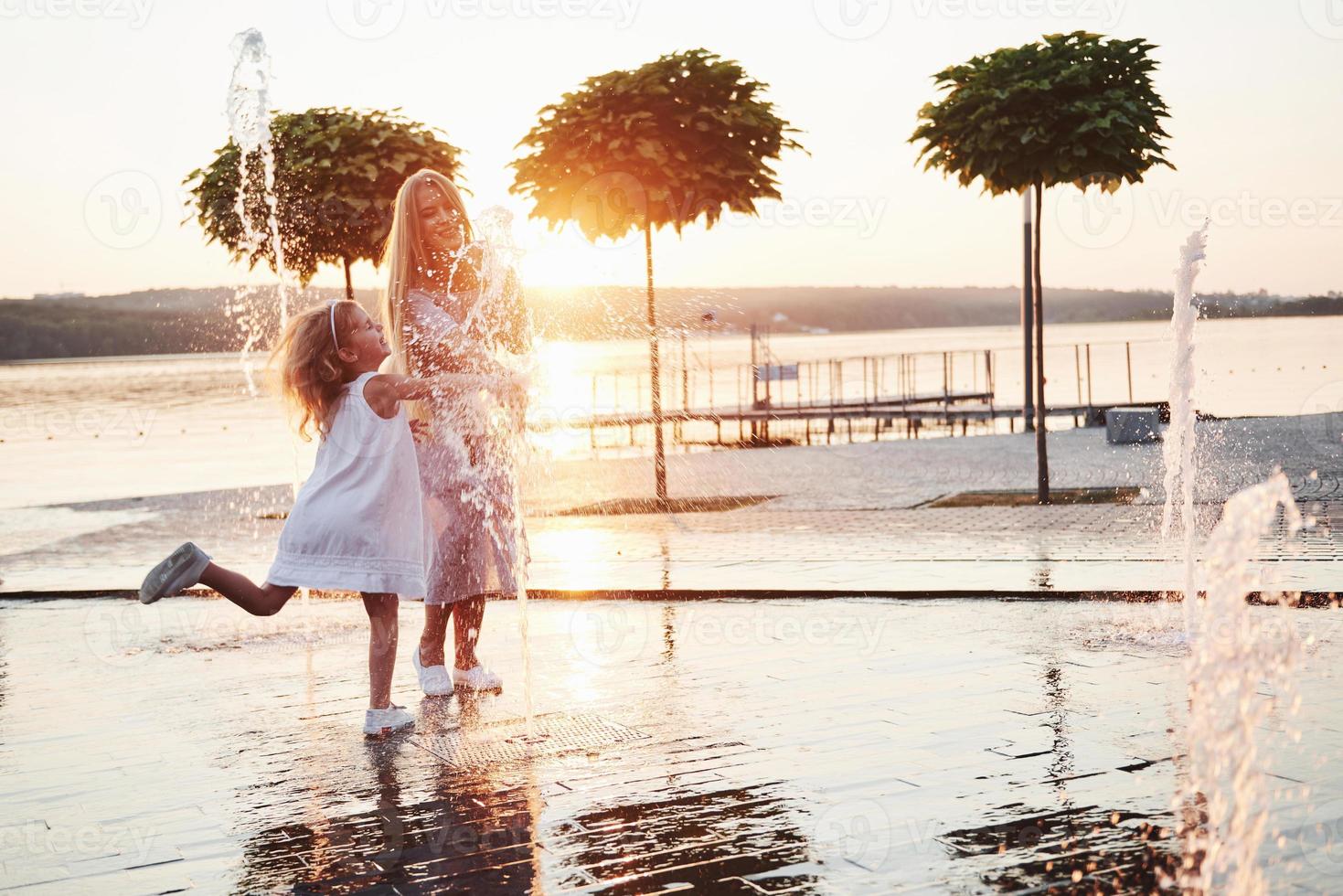 una donna che gioca con un bambino vicino all'oceano nel parco al tramonto foto