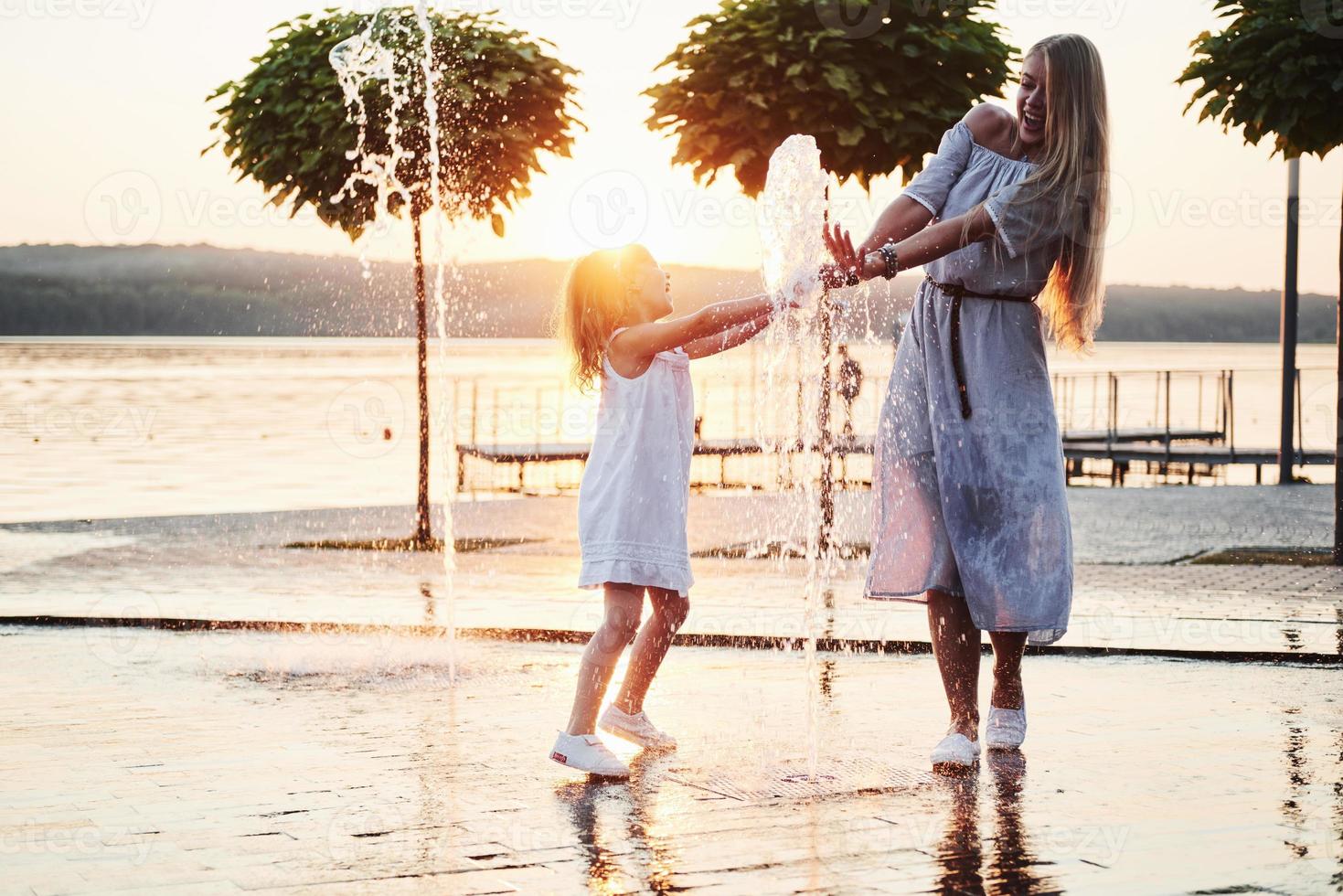 mamma con bambino vicino alla fontana al tramonto foto