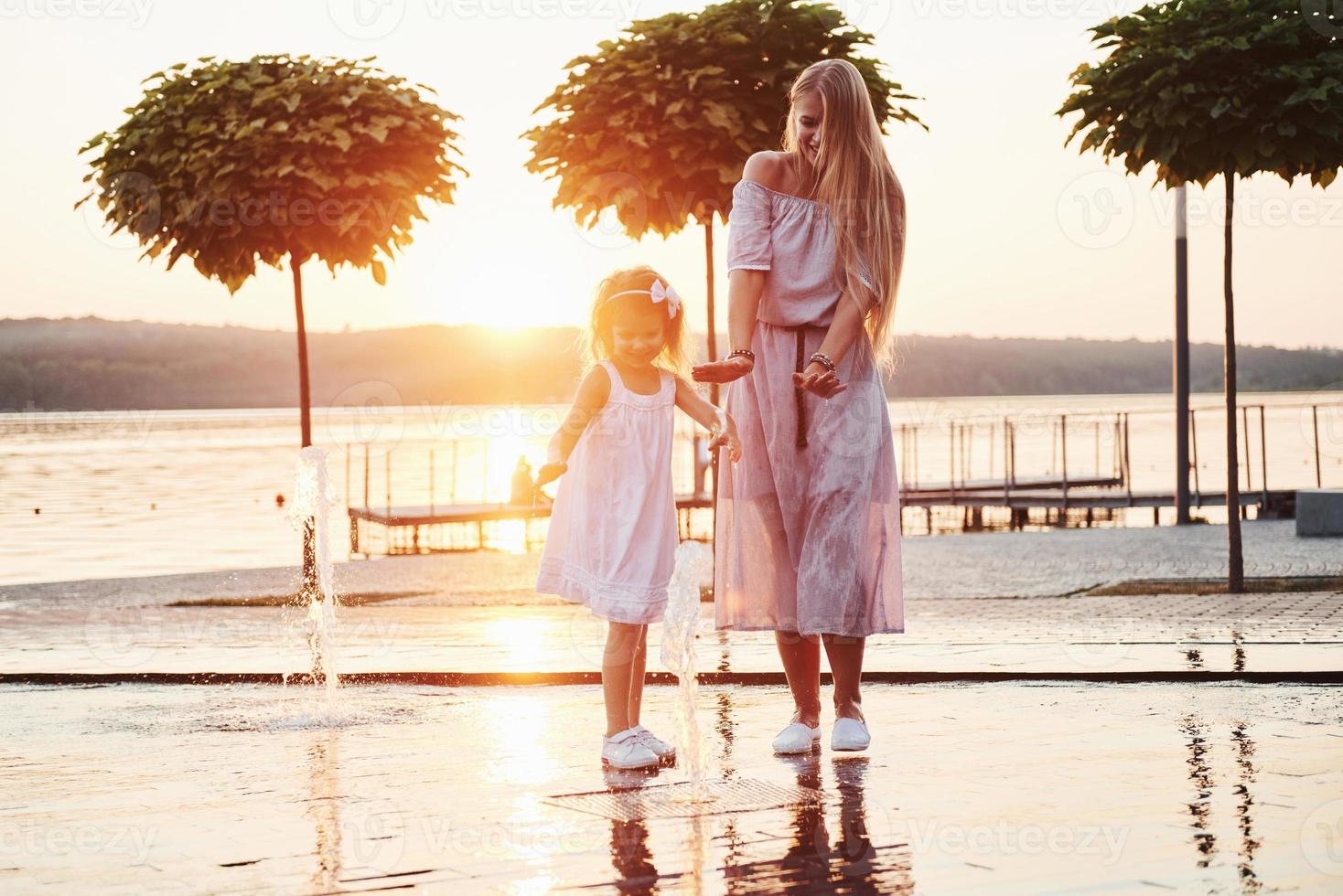 mamma con bambino vicino alla fontana al tramonto foto
