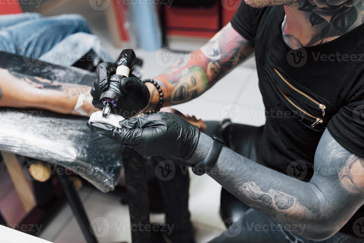 macchina per tatuaggi da vicino. maestro in guanti sterili neri che creano foto a portata di mano con esso in salone