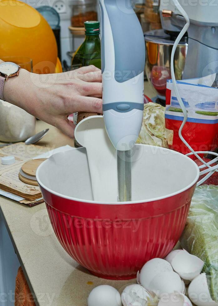 casalinga sbattere pancake pastella nel cucina con miscelatore e ciotola foto