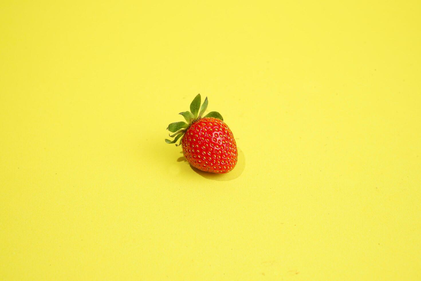 singolo fragola isolato su giallo sfondo foto