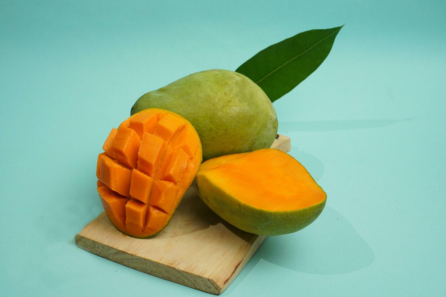 fresco Mango frutta con cubo fetta con giallo carne dentro isolato su taglio tavola blu sfondo contenere vitamina c foto