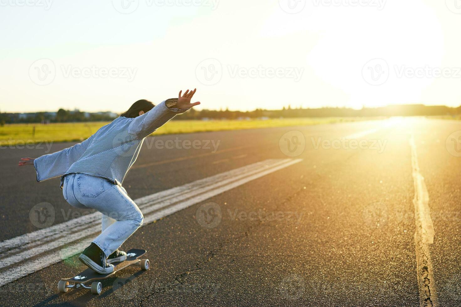 contento pattinatore ragazza equitazione sua skateboard e avendo divertimento su vuoto strada. sorridente donna godendo incrociatore cavalcata su soleggiato strada foto