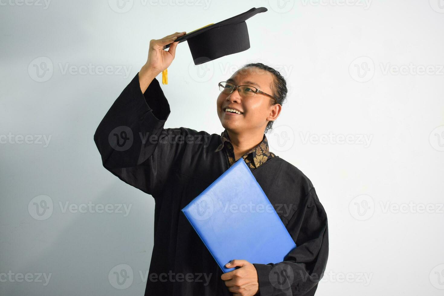 espressive di adulto Indonesia maschio indossare la laurea veste, cappello e occhiali, asiatico maschio la laurea portare vuoto blu certificato isolato su bianca sfondo, espressioni di ritratto la laurea foto