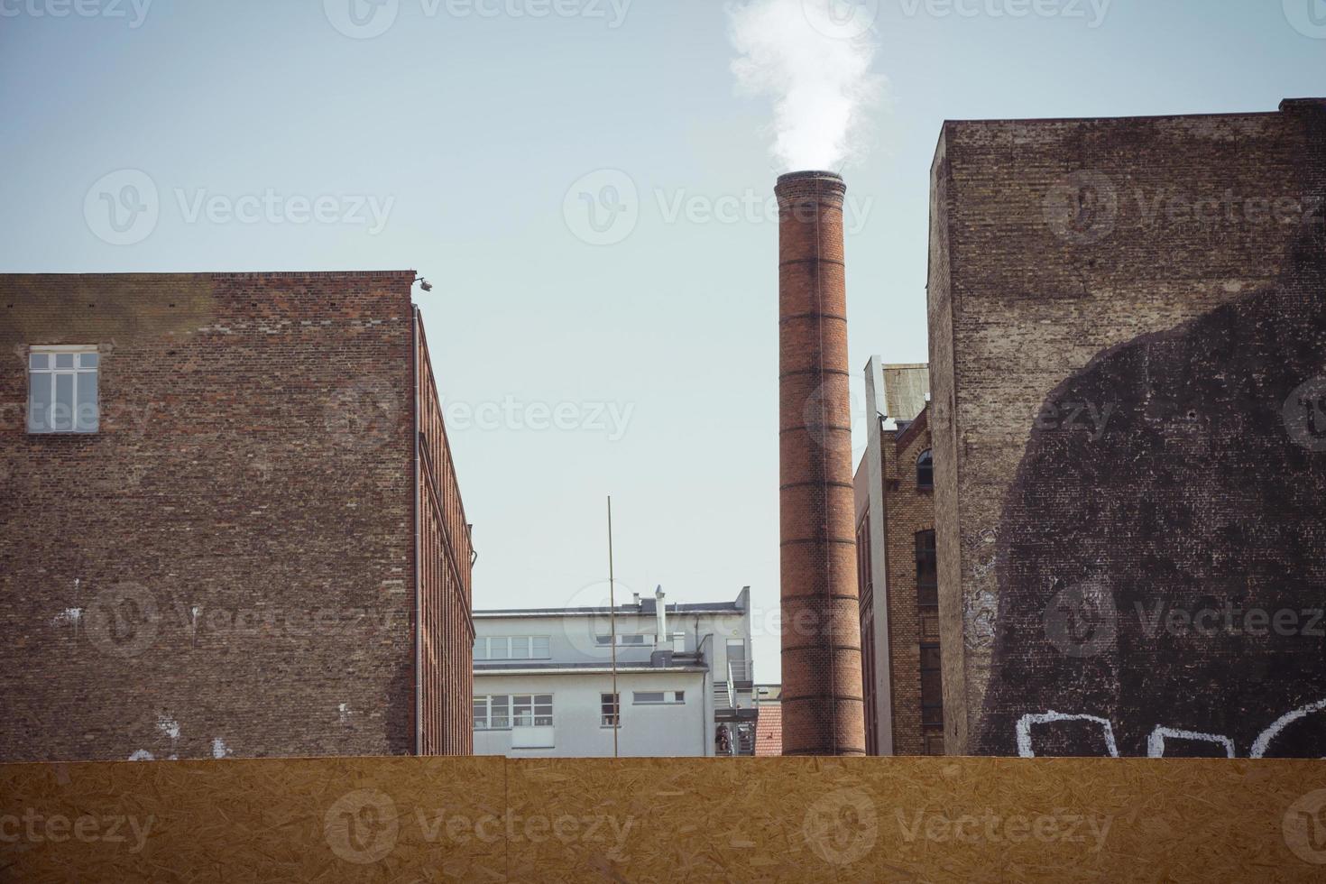fumo emesso da un camino industriale in mattoni in un vecchio edificio industriale foto