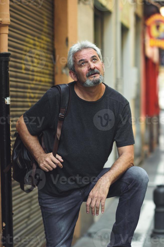 turista maturo uomo con zaino da viaggio in background urbano. foto