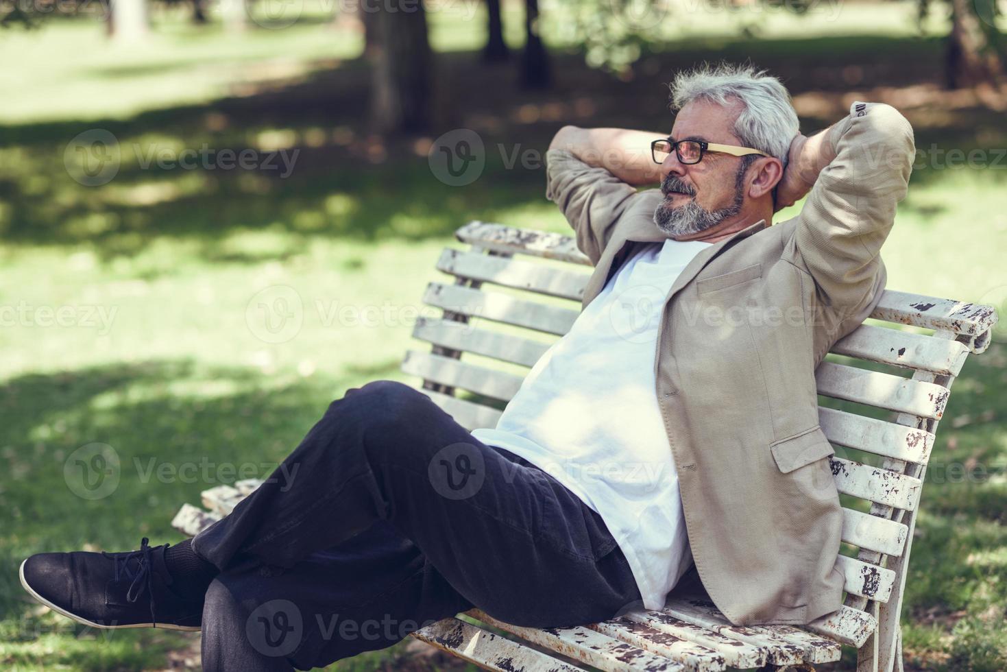 pensieroso uomo maturo seduto su una panchina in un parco urbano. foto