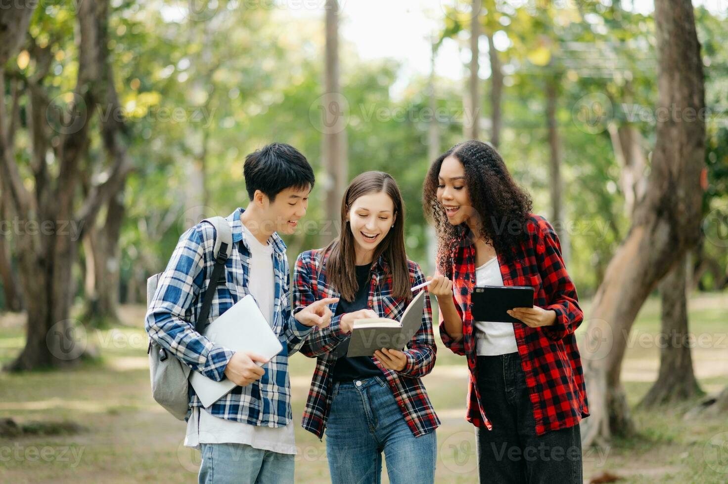 tre giovane Università studenti è lettura un' libro mentre rilassante seduta su erba nel un' città universitaria parco con sua gli amici. formazione scolastica concetto foto