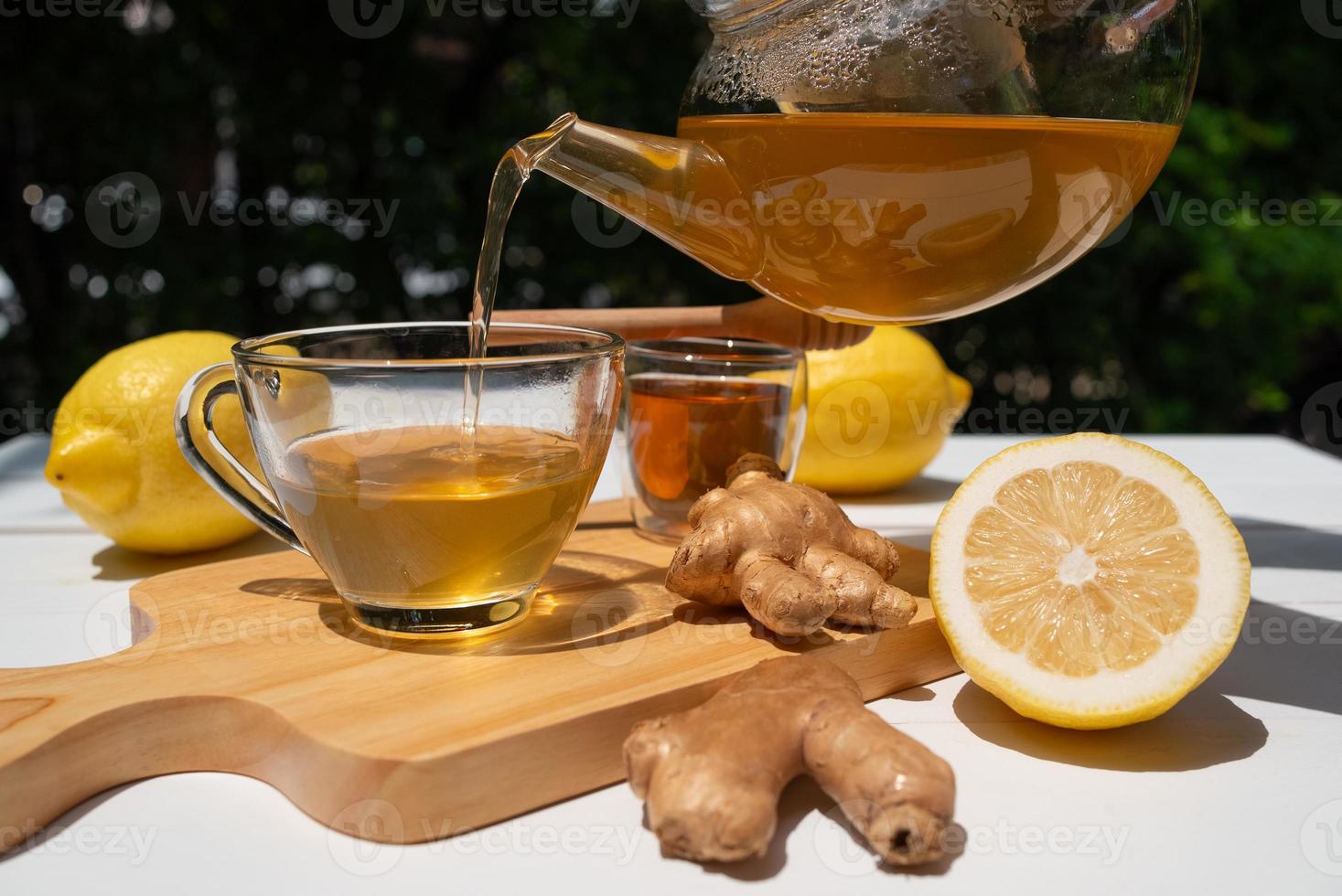 la limonata calda con lo zenzero nella teiera è stata versata nella tazza da tè e servita sul tavolo al bar foto