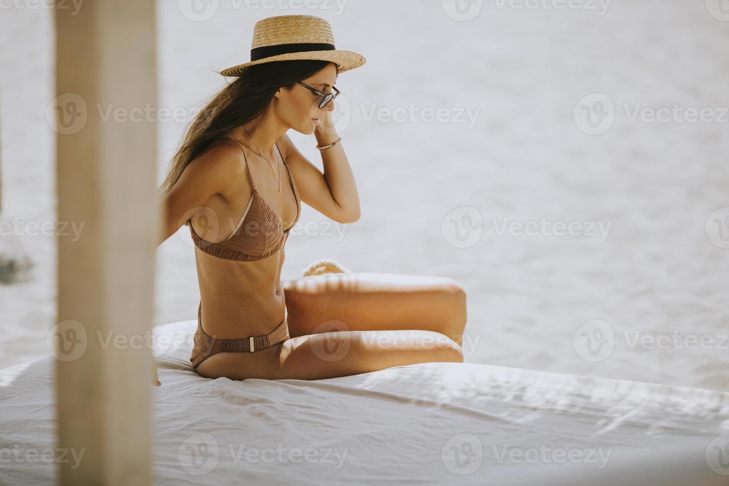 giovane donna con cappello e occhiali da sole che si rilassa nella lounge della spiaggia foto