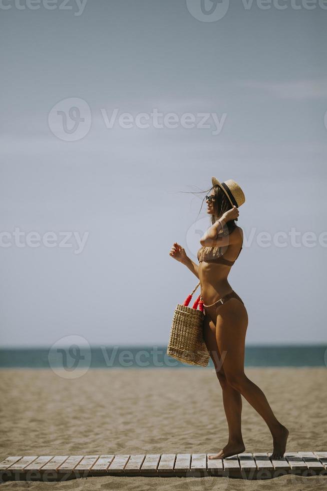 giovane donna in bikini che cammina su una spiaggia in estate foto