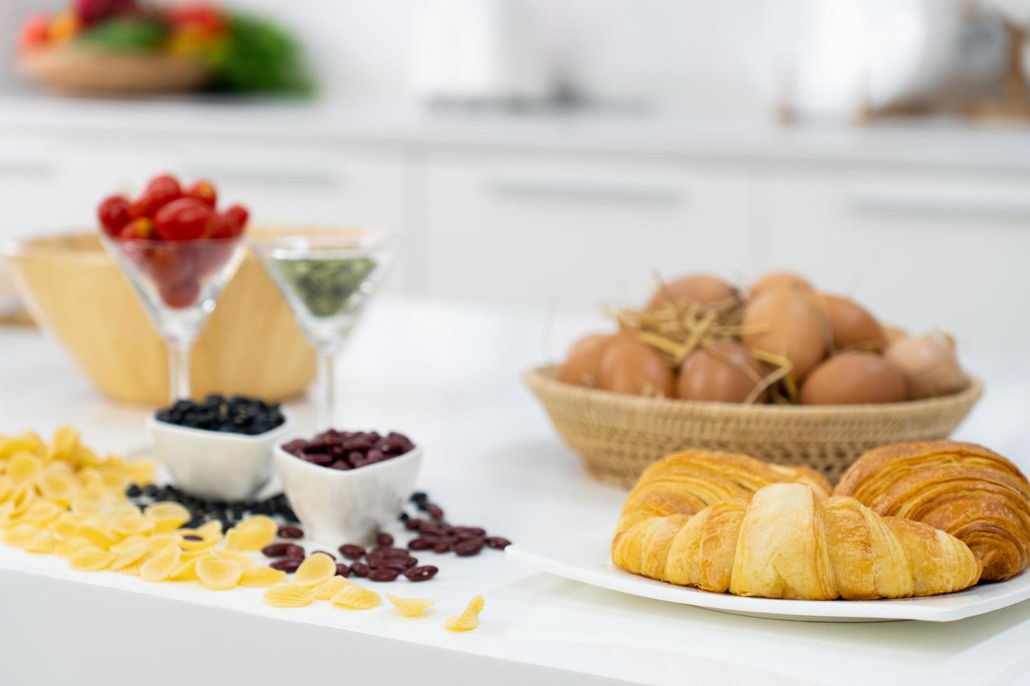 croissant, uova e fagioli sul tavolo in cucina, preparando per una sana colazione foto