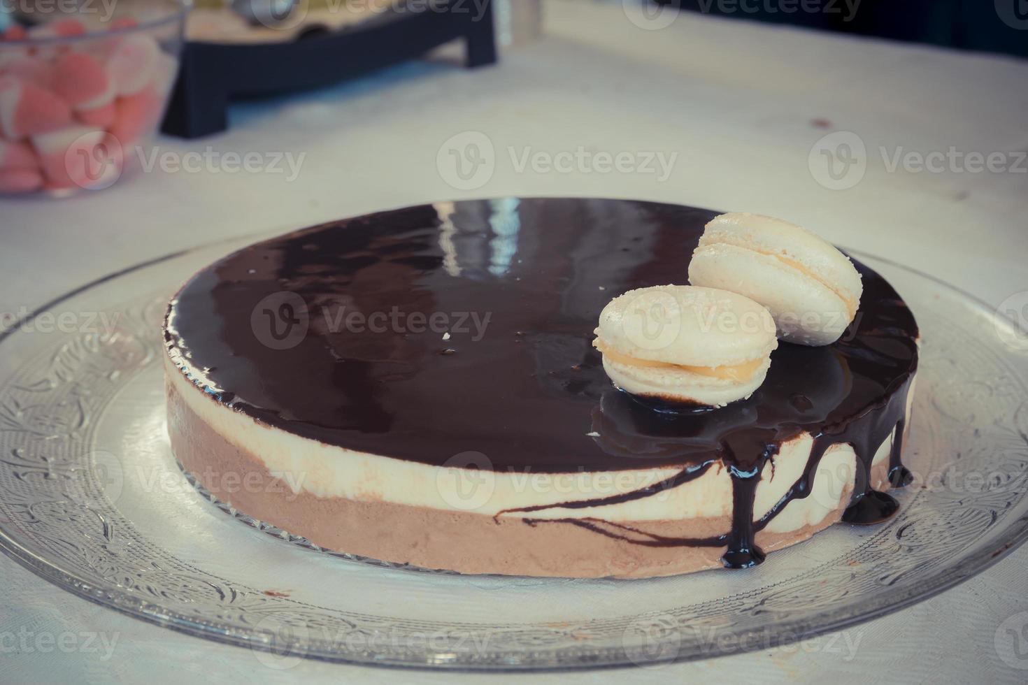 mousse cioccolato-vaniglia con glassa di cioccolato e due amaretti bianchi foto