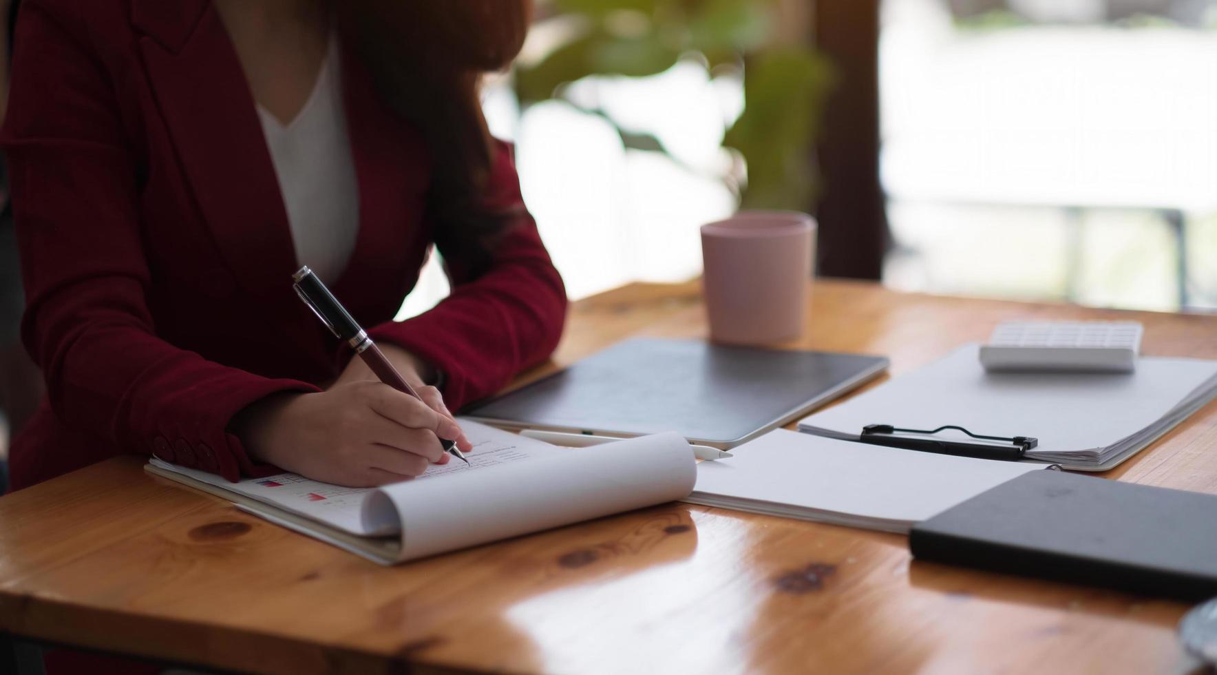 contabilità femminile o contabile che fornisce servizi di contabilità per piccole imprese, tenendo la penna per prendere appunti e utilizzando la calcolatrice, donna che utilizza tablet digitale e calcolatrice foto