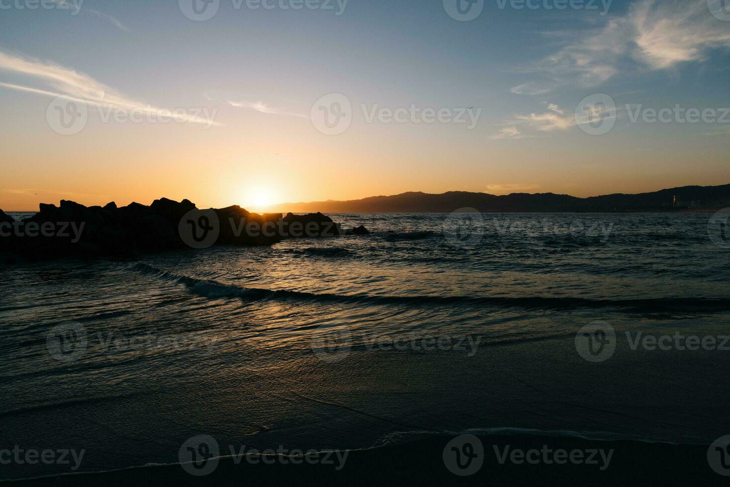 tramonto dietro a il rocce su il spiaggia foto