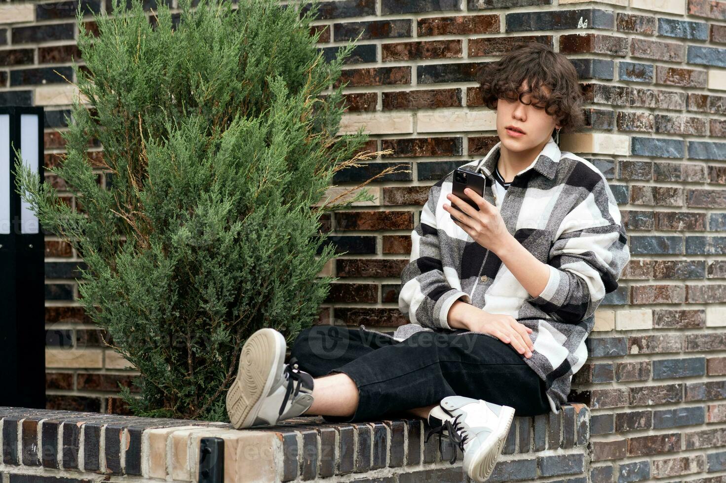giovane uomo legge qualcosa su il Telefono mentre seduta nel il parco foto