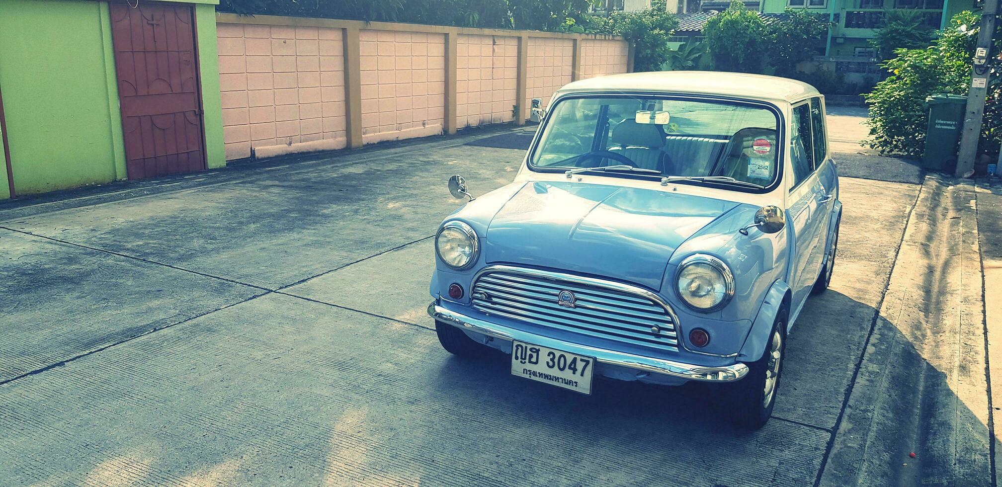 bangkok, Tailandia- settembre 29, 2023 blu e bianca classico mini bottaio auto parcheggiata su strada con luce del sole e copia spazio nel Vintage ▾ colore stile.trasporto, Vintage ▾ e retrò veicolo concetto. foto