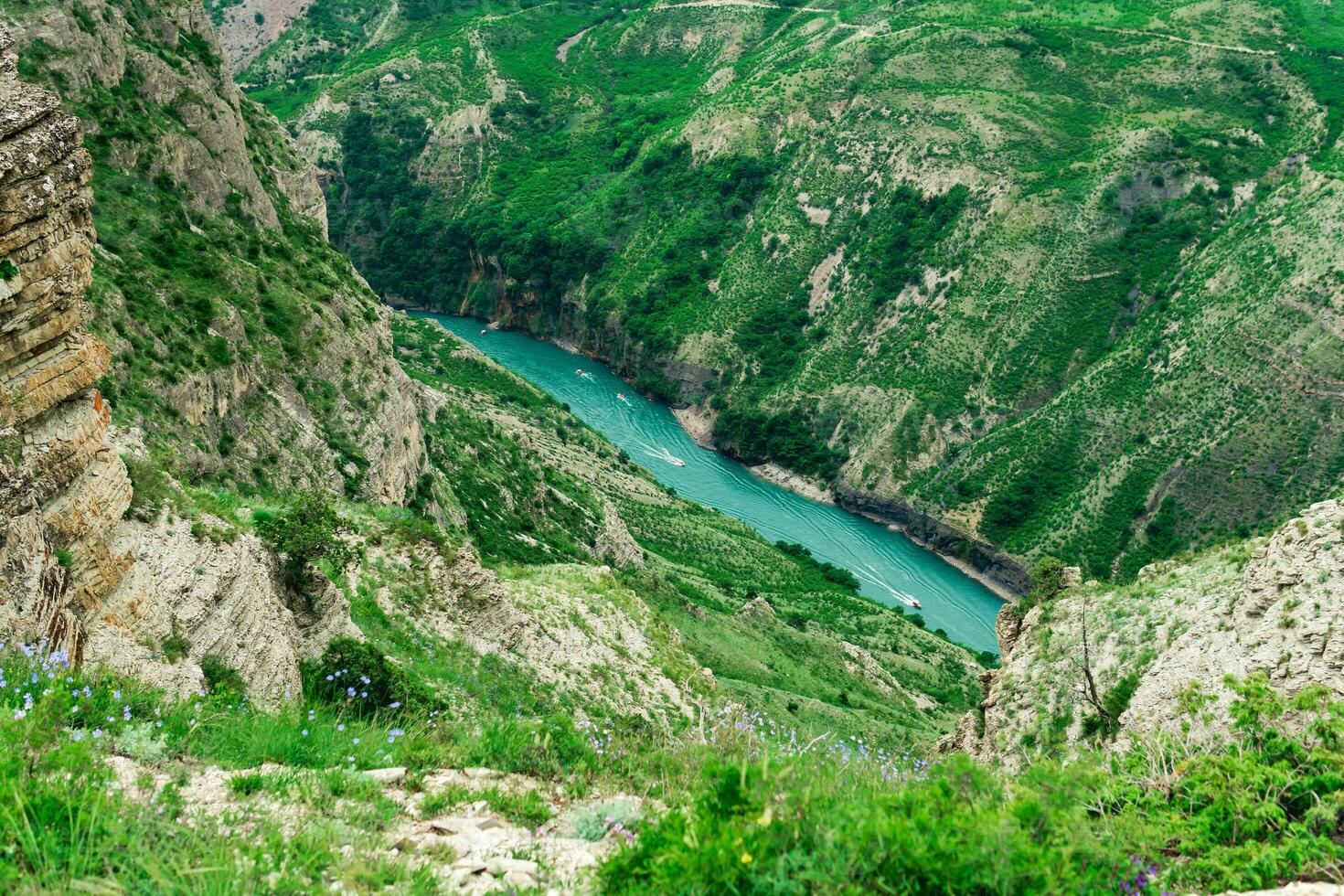 montagna paesaggio con un' in profondità canyon con un' blu fiume lungo quale un' il motore barca si sposta foto