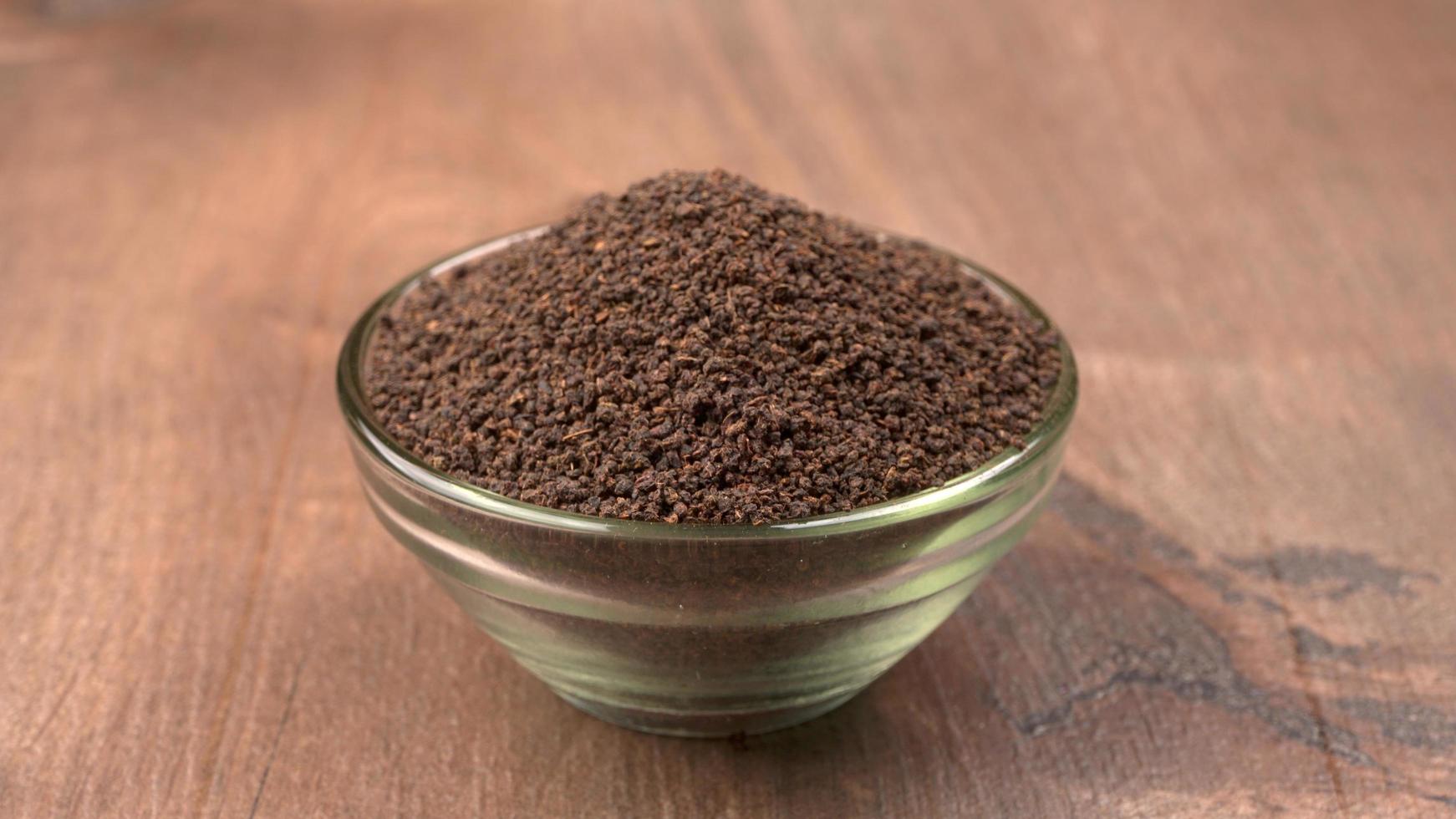 tè nero in polvere o polvere secca di tè in polvere, chai patti isolato in una ciotola di legno. foto